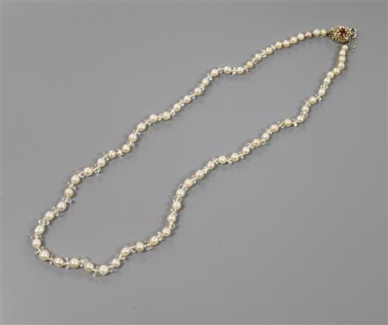 A single strand cultured pearl necklace with paste spacers and early 20th century yellow metal, hessonite garnet and diamond clasp.